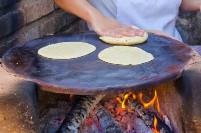 Offenes Feuer mit Metallplatte, auf der Tortillas gebacken werden.
