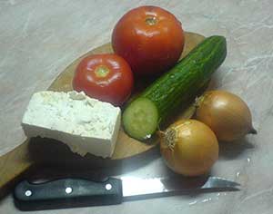 Holzbrett mit Tomaten, Gurken, Zwiebeln und Salzlake-Käse - die typischen Zutaten des Schopska-Salats.