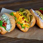 Drei verschiedene Hot Dogs auf Holztisch