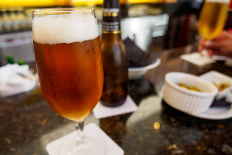 Glas mit spanischem Bier, im Hintergrund Flasche und Schale Oliven