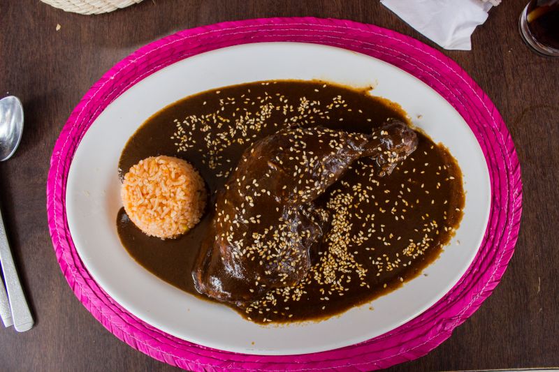 Mole Poblano auf Teller über Hühnchenkeule und etwas Reis