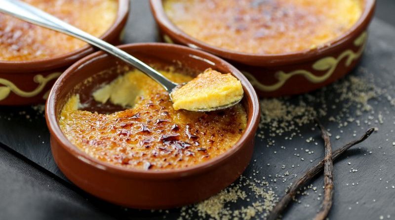 Schälchen mit Crèmes Brulées, ein Löffel bereits entnommen