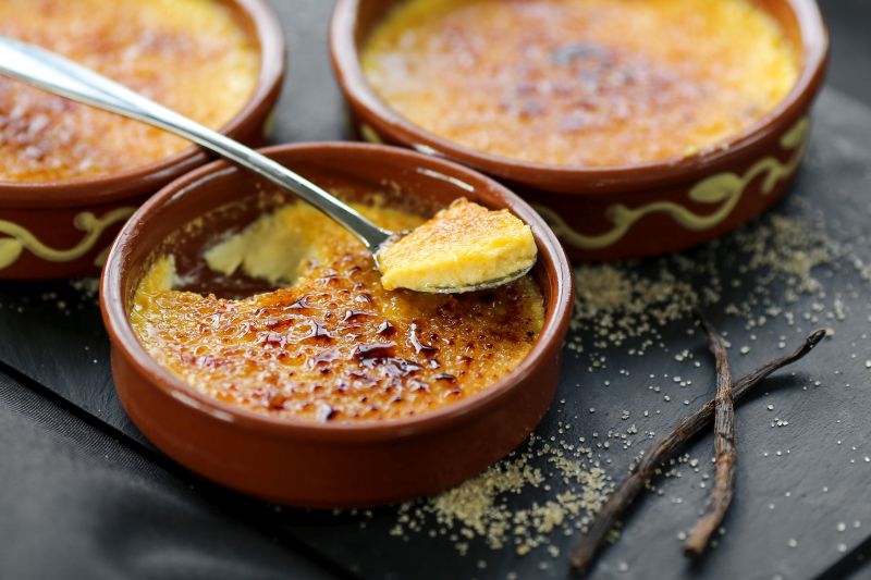 Schälchen mit Crèmes Brulées, ein Löffel bereits entnommen