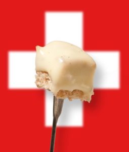 Gabel mit Brot und Käse aus Käsefondue vor Schweizer Flagge
