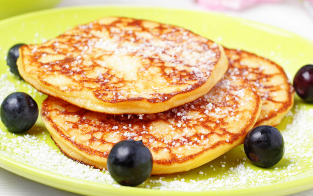 Pfannkuchen mit Puderzucker auf gelbem Teller