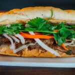 Bánh mì belegt von vorne: gut zu sehen Korianderblätter, eingelegte Karotten und Rettich.